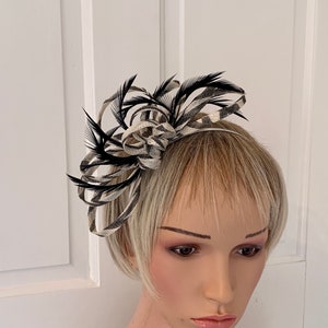 May include: A black and white checked fabric hair clip with black feathers. The clip is worn on a mannequin's head.