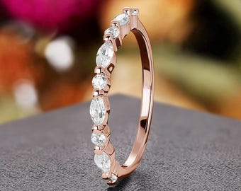May include: A delicate rose gold band ring with a row of marquise-shaped clear gemstones.