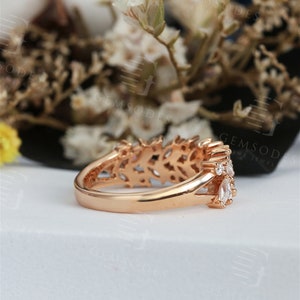 Puede incluir: Anillo de oro rosa con un delicado dise&ntilde;o calado y varias piedras claras y brillantes. El anillo presenta una fila de piedras con forma de marquesa y piedras redondas m&aacute;s peque&ntilde;as, engastadas en una banda detallada.