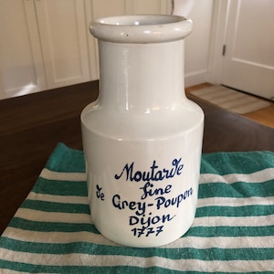 May include: White ceramic mustard jar with blue lettering that reads "Moutarde Fine de Grey-Poupon Dijon 1777".