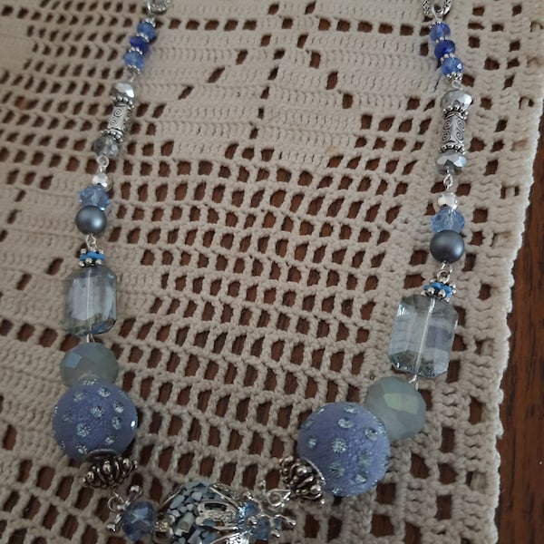 Sautoir avec cordon suédine bleu, perles pavés de nacre, perles de cristal, perles de strass, intercalaires en métal et fermoir toogle.