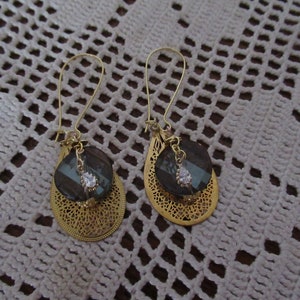 Örhängen med guldfärgad infattning, filigran guldfärgad tår, skimrande brun tvinnad pärla omgiven av guldfärgade blomkupor, hänge i strass