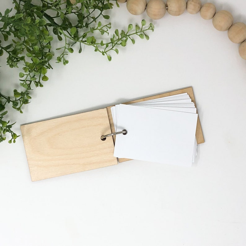 May include: A small wooden book with a metal ring binding. The book is open to reveal blank white cards.
