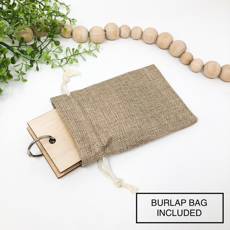 May include: A set of wooden blank tags with a silver ring, tied with a twine string and placed inside a burlap bag. The text "BURLAP BAG INCLUDED" is printed below the image.