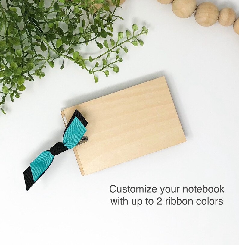 May include: A wooden notebook with a teal and black ribbon tied around it. Customize your notebook with up to 2 ribbon colors.
