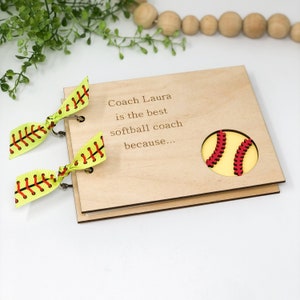 May include: A wooden scrapbook with a softball cutout and the text "Coach Laura is the best softball coach because..."  The scrapbook has yellow and red ribbon ties.