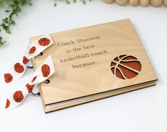 Könnte beinhalten: Ein Holz-Fotoalbum mit einem Basketball-Ausschnitt und dem Text "Coach Shannon ist der beste Basketballtrainer, weil..." Das Fotoalbum hat zwei weiße Bänder mit aufgedruckten orangefarbenen Basketbällen.