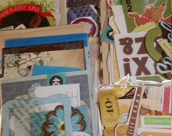 May include: A collection of scrapbook ephemera, including paper cutouts, tags, and cards. The assortment features a variety of colors, shapes, and designs, including floral patterns, a guitar, and the words "NAUGHTY LIST".