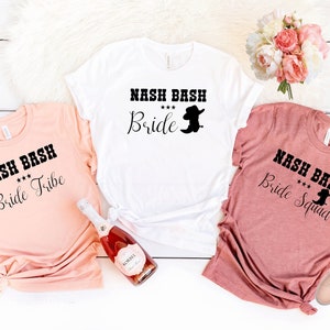 May include: Three white t-shirts with black text and a silhouette of a cowboy boot. The shirts read "Nash Bash Bride", "Nash Bash Bride Tribe", and "Nash Bash Bride Squad".