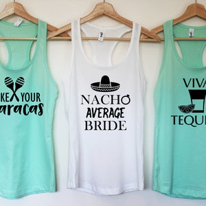 Puede incluir: Tres camisetas sin mangas con tem&aacute;tica de fiesta mexicana. La primera camiseta sin mangas es azul turquesa con el texto "Shake Your Maracas" y un par de maracas. La segunda camiseta sin mangas es blanca con el texto "Nacho Average Bride" y un sombrero. La tercera camiseta sin mangas es azul turquesa con el texto "Viva Tequila" y un vaso de chupito con una rodaja de lima.