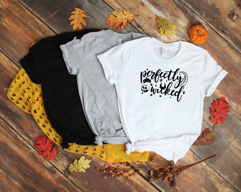 May include: Three t-shirts with different colors, black, gray, and white. The white t-shirt has a black graphic that says "perfectly wicked" with a crown, skull, and a wrench.