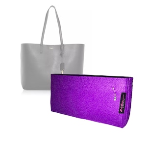 May include: A rectangular purple felt bag organizer with a black fabric tag featuring the text Felt Bag Organizer by Saga Mouth. The organizer is positioned in front of a grey tote bag with thin shoulder straps and a small hanging luggage tag.