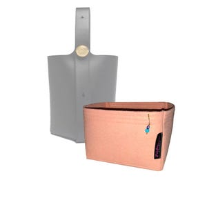 May include: A peach-colored felt bag insert with a blue and white evil eye charm. The insert is designed to fit inside a gray leather handbag.