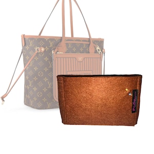 Può includere: Un organizer per borsa in feltro marrone di forma rettangolare con apertura superiore. Sul lato è presente una piccola etichetta in tessuto nero con la scritta rosa 'Felt Bag', dotata di una spilla da balia dorata con un ciondolo a occhio blu.