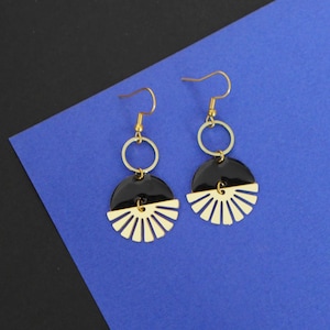 Peut inclure: Une paire de boucles d'oreilles en or avec émail noir et blanc. Les boucles d'oreilles présentent un design en demi-cercle avec une découpe en forme d'éventail.