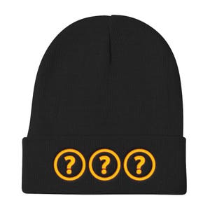 May include: Black knit beanie with a fold-over cuff and three yellow question marks on the front.