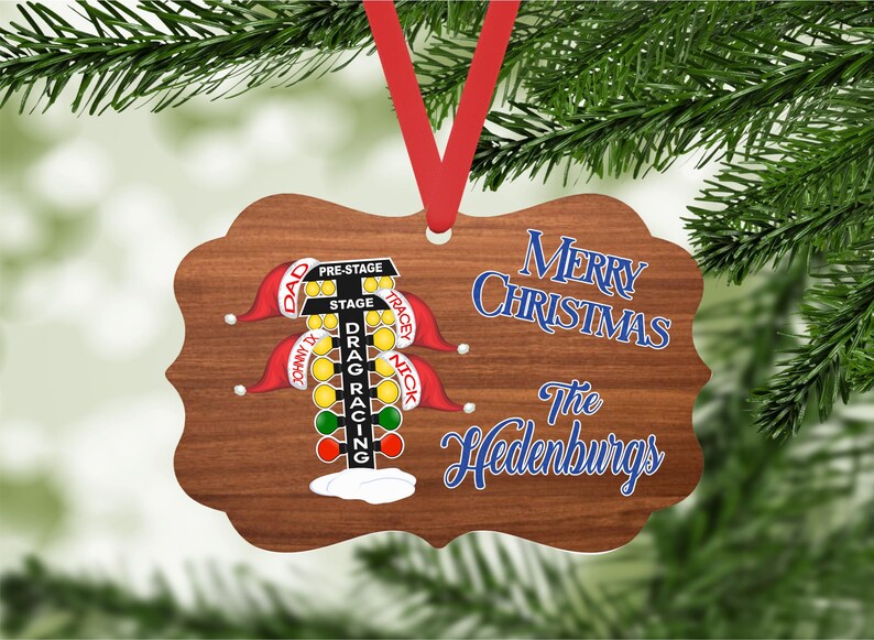 May include: A wooden Christmas ornament with a drag racing Christmas tree light display. The ornament is decorated with red and green lights, and the text "Merry Christmas The Hedenburgs" is written in blue on the ornament.