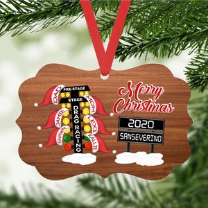 May include: A wooden Christmas ornament shaped like a drag racing Christmas tree with the words "Merry Christmas 2020 SANSEVERINO" on it.