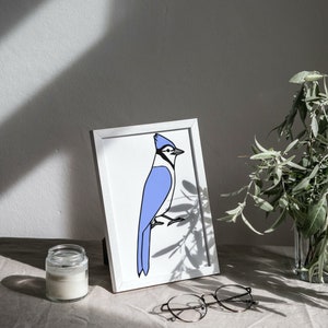 a blue bird sitting on top of a table next to a vase of flowers