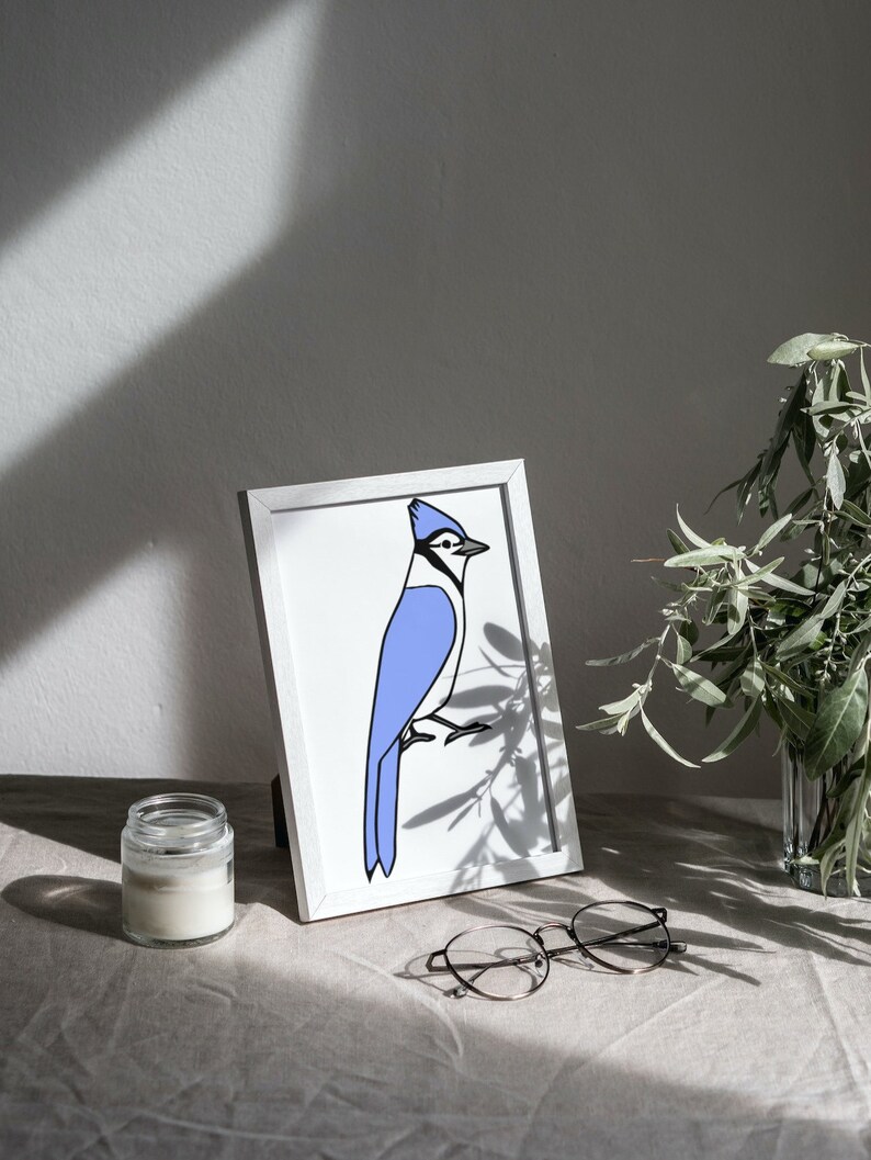 a blue bird sitting on top of a table next to a vase of flowers
