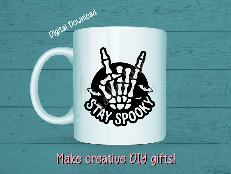 May include: White ceramic mug with a black graphic of a skeleton hand making a rock-and-roll gesture, with the words "STAY SPOOKY" and bats. The words "Digital Download" and "Make creative DIY gifts!" are also visible.