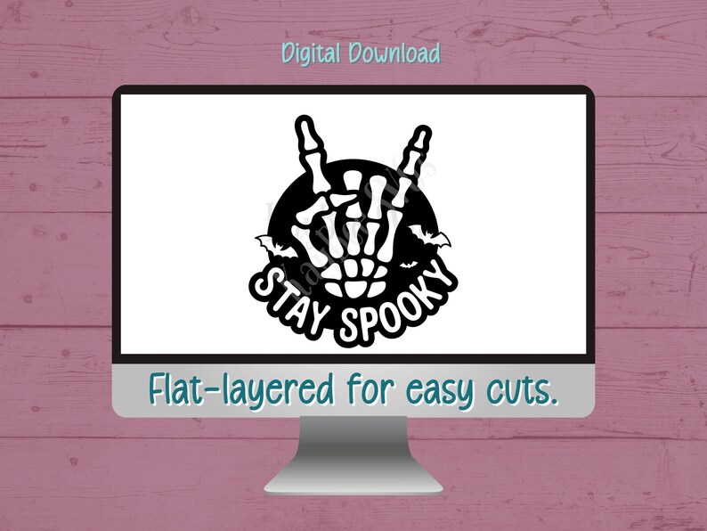 May include: A computer screen displays a black and white Halloween-themed graphic. The design features a skeleton hand making a rock-and-roll gesture, surrounded by bats and the words "STAY SPOOKY." The text "Digital Download" and "Flat-layered for easy cuts" are also visible.