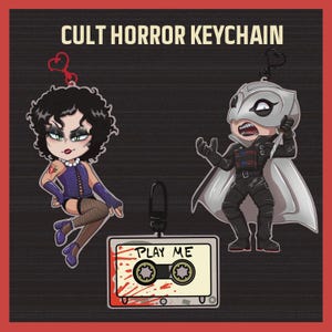 May include: Cult horror keychain set with two cartoon characters and a cassette tape. One character is a woman in a corset and the other is a masked figure holding a knife. The cassette tape has the words "PLAY ME" and blood splatter.