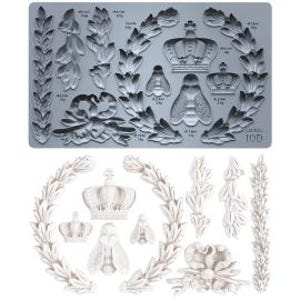 May include: A gray silicone mold featuring various decorative elements, including crowns, bees, laurel wreaths, and floral designs. The mold is designed for creating detailed embellishments for crafts and projects. The image also shows several white resin castings made from the mold.