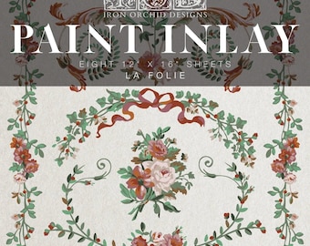 May include: A paint inlay set with floral and botanical patterns. The set contains eight sheets, each measuring 30.5 x 40.6 cm. The design includes roses, greenery, and a ribbon, with the text "PAINT INLAY" and "LA FOLIE".