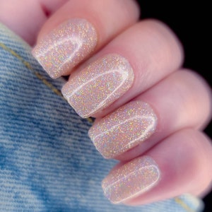 May include: Close-up of four fingernails with a light pink, iridescent glitter nail polish.