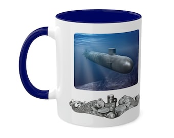 May include: White ceramic coffee mug with a blue rim and handle. The mug features a graphic of a submarine underwater and a silver submarine insignia with two fish.