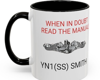May include: White ceramic mug with a black rim and handle. The mug has a black and white submarine graphic and the text "When in doubt read the manual" and "YN1 (SS) SMITH".