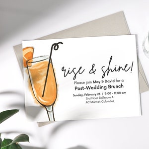 May include: A white card with a hand-drawn illustration of a mimosa cocktail. The text on the card reads "rise & shine! Please join May & David for a Post-Wedding Brunch Sunday, February 23 | 9:00 - 11:00 am 3rd Floor Ballroom A AC Marriot Columbus"