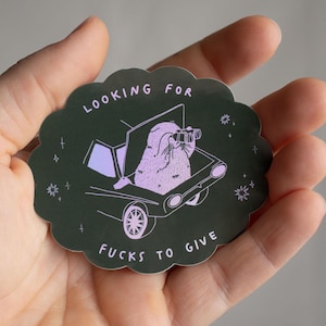 À la recherche d'une baise à offrir 2,0 | Sticker chat holographique représentant un chat assis dans le coffre d'une voiture cherchant des conneries à lui donner avec des jumelles