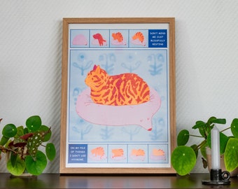May include: A framed illustration of a cat sleeping on a pink cloud. The illustration is surrounded by a blue background with white snowflakes. The text on the illustration reads "Don't mind me just blissfully resting" and "On my pile of things I don't use anymore".