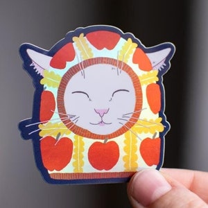 Cagoule Apple Chat | Adorable autocollant holographique en vinyle représentant un chat blanc portant une cagoule à motif pomme