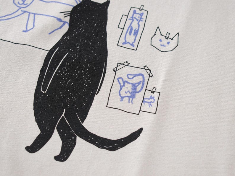 Cat gallery t-shirt | Hand screen printed on beige organic cotton tee with black and blue illustration of a cat judging his own art image 8