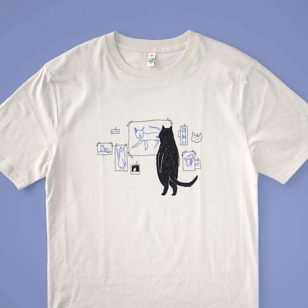 Cat gallery t-shirt | Hand screen printed on beige organic cotton tee with black and blue illustration of a cat judging his own art