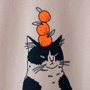Oranje Kat t-shirt Met de hand gezeefdrukte illustratie van een kat die sinaasappels balanceert op een mistig roze T-shirt van biologisch katoen met marineblauw en oranje afbeelding 3
