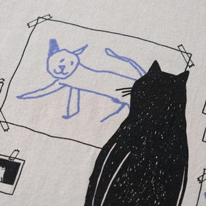 Cat gallery t-shirt | Hand screen printed on beige organic cotton tee with black and blue illustration of a cat judging his own art image 7