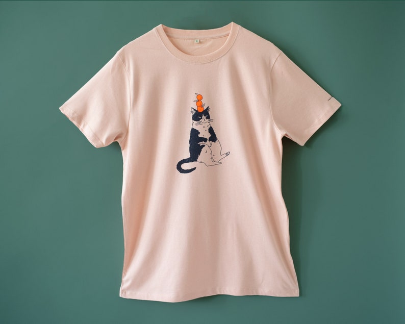 Oranje Kat t-shirt Met de hand gezeefdrukte illustratie van een kat die sinaasappels balanceert op een mistig roze T-shirt van biologisch katoen met marineblauw en oranje afbeelding 4