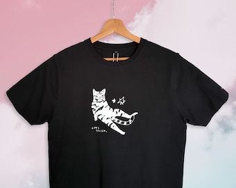 Das Leben ist hart | Katzen-T-Shirt, illustrierte sitzende Tabby-Katze im Siebdruck auf schwarzem Bio-Baumwoll-T-Shirt mit wasserbasierter weißer Tinte, Life is