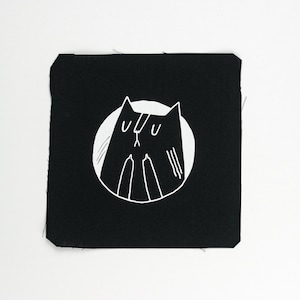 Könnte beinhalten: Ein schwarzer quadratischer Aufnäher mit einer weißen Illustration einer Katze in einem weißen Kreis. Die Katze hat ein minimalistisches Design mit großen Augen und einer kleinen Nase. Der Aufnäher hat einen rohen Rand.