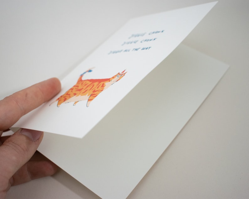 May include: A greeting card with a cartoon orange tabby cat with blue eyes and a blue bow on its tail. The text on the card reads "You can't just give up on the way".