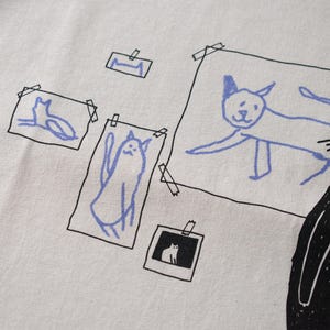 Cat gallery t-shirt | Hand screen printed on beige organic cotton tee with black and blue illustration of a cat judging his own art image 9