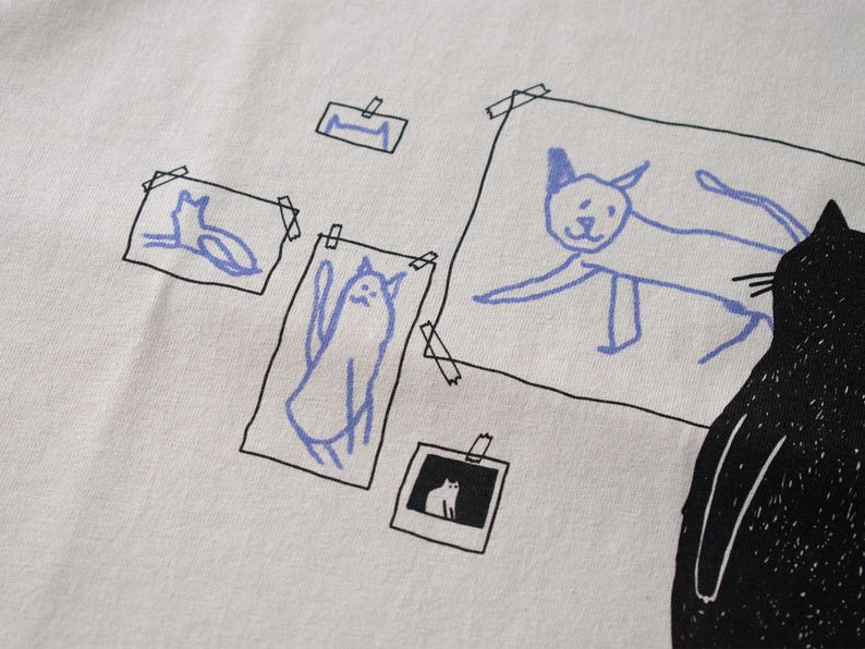 Cat gallery t-shirt | Hand screen printed on beige organic cotton tee with black and blue illustration of a cat judging his own art image 9