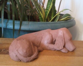 Sculpture of a dog lying in terracotta Brown