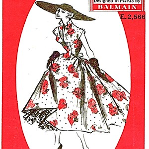 May include: A black and white illustration of a woman wearing a white dress with red flowers and a wide-brimmed hat. The dress is a "Frock" pattern designed by Balmain. The text "This is a Woman's Illustrated Couture Pattern" is at the top of the image. The text "Designed in Paris by Balmain" is in a red box. The text "E. 2,566" is below the red box. The text "What Home Tested Means" is in a red box at the bottom of the image. The text "Every pattern which carries the "Home Tested" label has been made up successfully by an amateur dressmaker." is below the red box. The text "Frock 6 Pieces" is at the bottom right of the image.