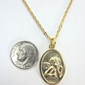 Puede incluir: Un collar de cadena de oro con un colgante ovalado de oro que presenta un querub&iacute;n con alas. El colgante tiene la palabra "Italia" inscrita en la parte inferior.