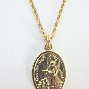 Puede incluir: Collar de cadena dorada con un colgante ovalado dorado que representa a un &aacute;ngel de la guarda con las palabras "Guardian Angel" y "Truly" inscritas en el colgante.
